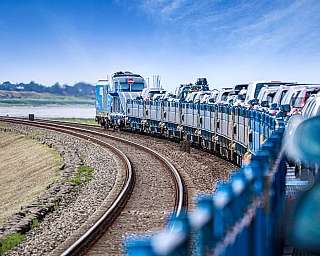 Der blaue AUTOZUG fährt vollbeladen über den Syltdamm mit Blick über das Wattenmeer.