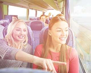 Zwei Frauen sitzen in einem Reisebus, der mit dem blauen AUTOZUG Sylt nach Sylt verkehrt.
