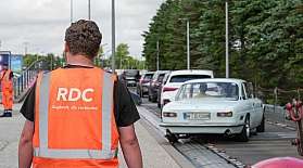 Es fahren PKW über die Laderampe auf den blauen AUTOZUG Sylt. Im Vordergrund steht ein Mitarbeiter mit dem Rücken zur Kamera.