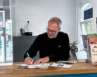 An employee of the RDC Deutschland Gruppe is showing a flyer in the RDC Kundencenter Niebüll.