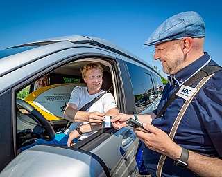 Staff member of the blue AUTOZUG Sylt checks customers in the vehicle.