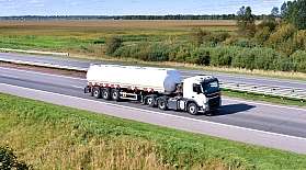 Ein LKW mit Gefahrtgut fährt auf einer Autobahn durch eine grüne Landschaft.