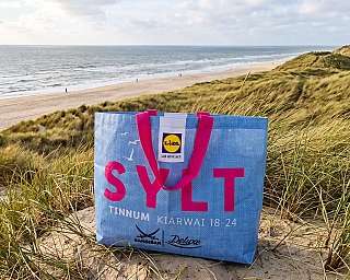 KI-Visual: Die Sylttüüt vom blauen AUTOZUG Sylt steht in den Dünen vor traumhafter Strandkulisse.