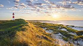 Dünenlandschaft, Leuchtturm und Strand auf Sylt bei Sonnenuntergang.