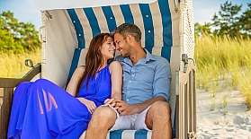 Ein Päärchen sitzt auf Sylt in einem Strandkorb am Strand.